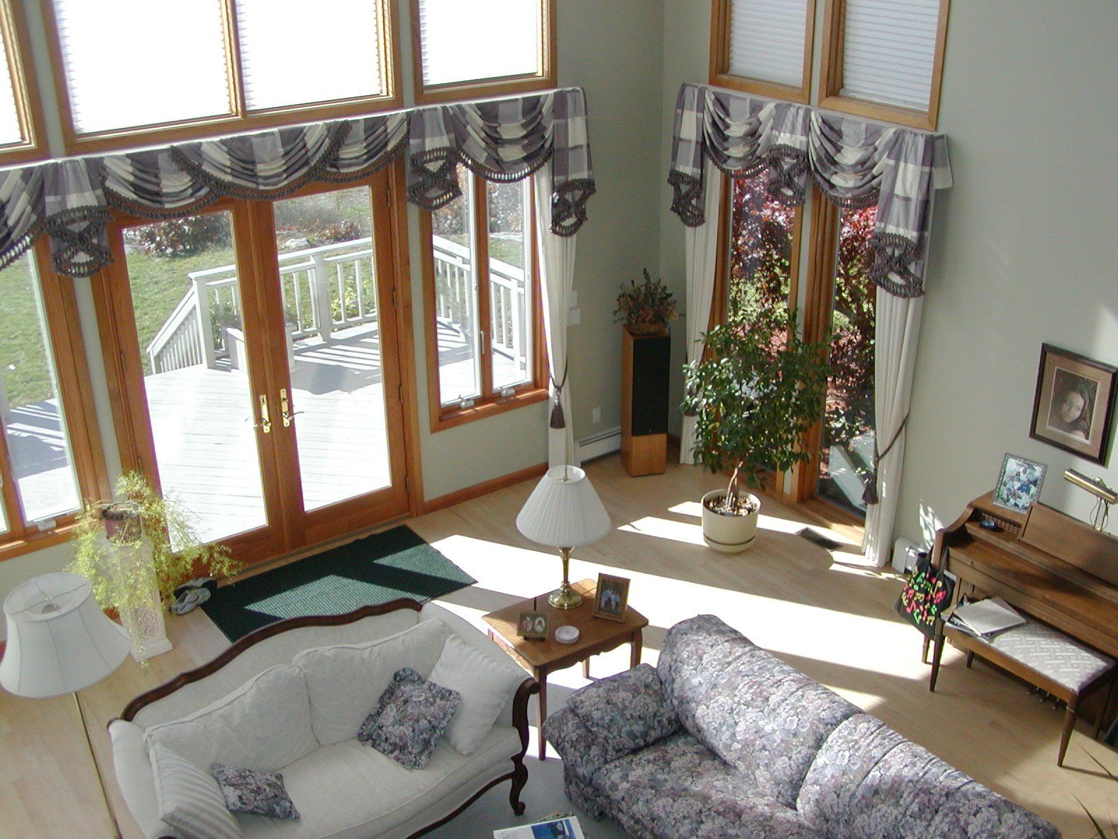 Living room with high ceilings, large windows, and two floral-patterned sofas.