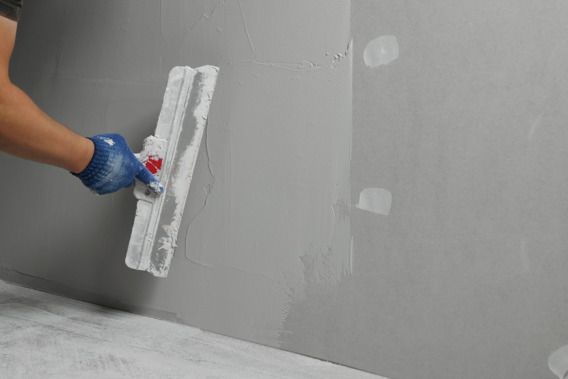 Professional worker plastering wall with putty knife.