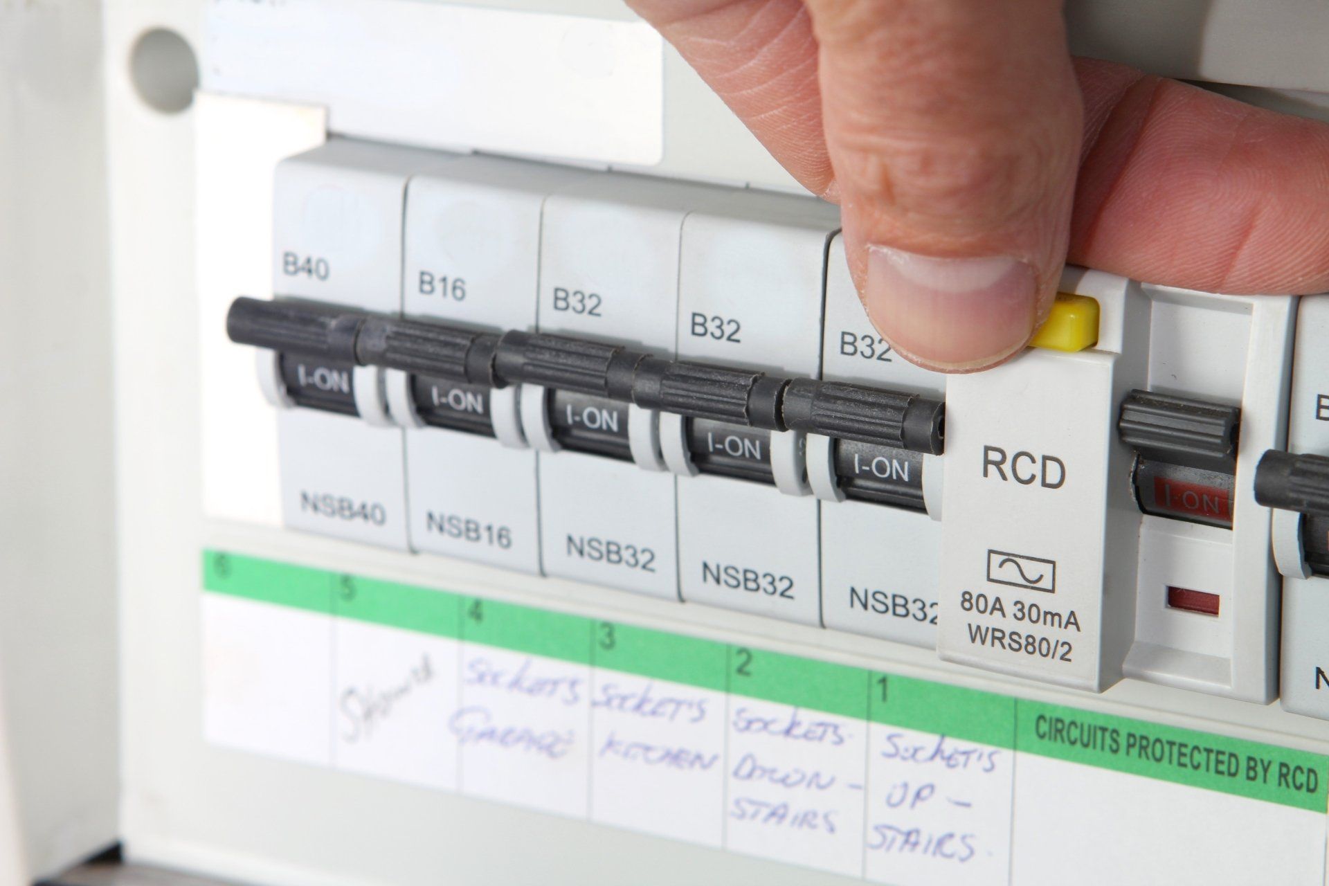 A person is pressing a button on a circuit breaker or fuseboard