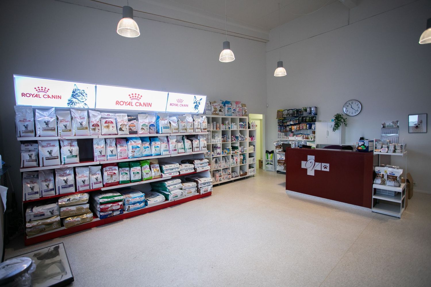 Pet store interior with shelves stocked with pet food and a red reception desk.
