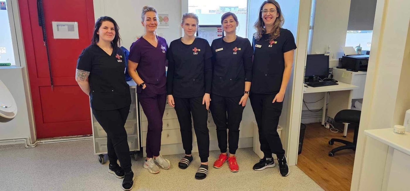 Five people in medical scrubs stand in a medical office.