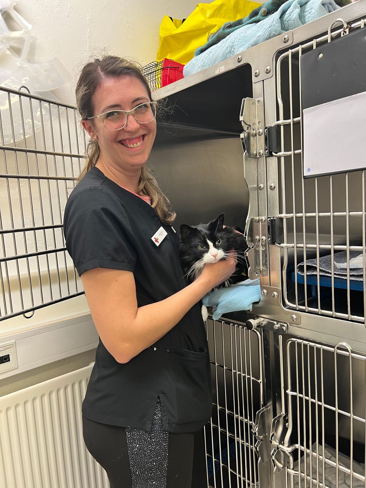 Veterinarian holding a wet black and white cat, smiling in a clinic.
