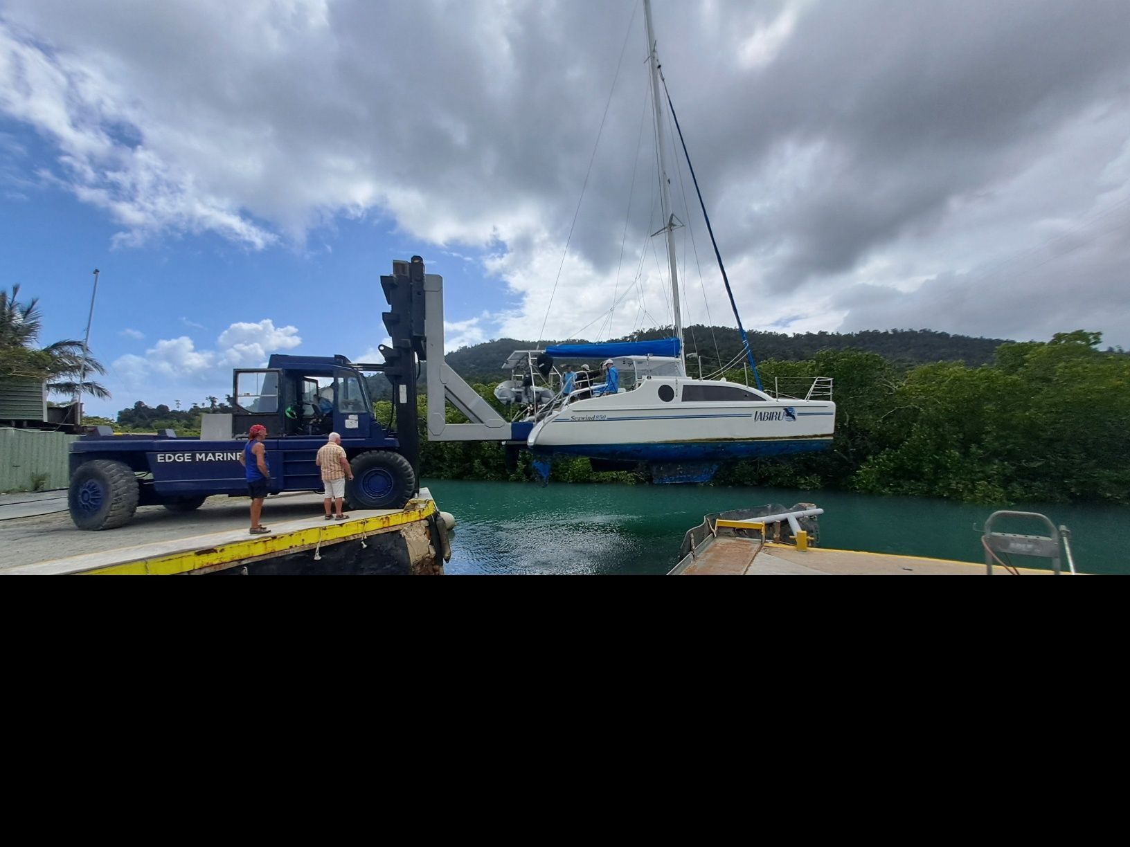A boat is being lifted into the water by a forklift — Edge's Boatyard In Jubilee Pocket, QLD