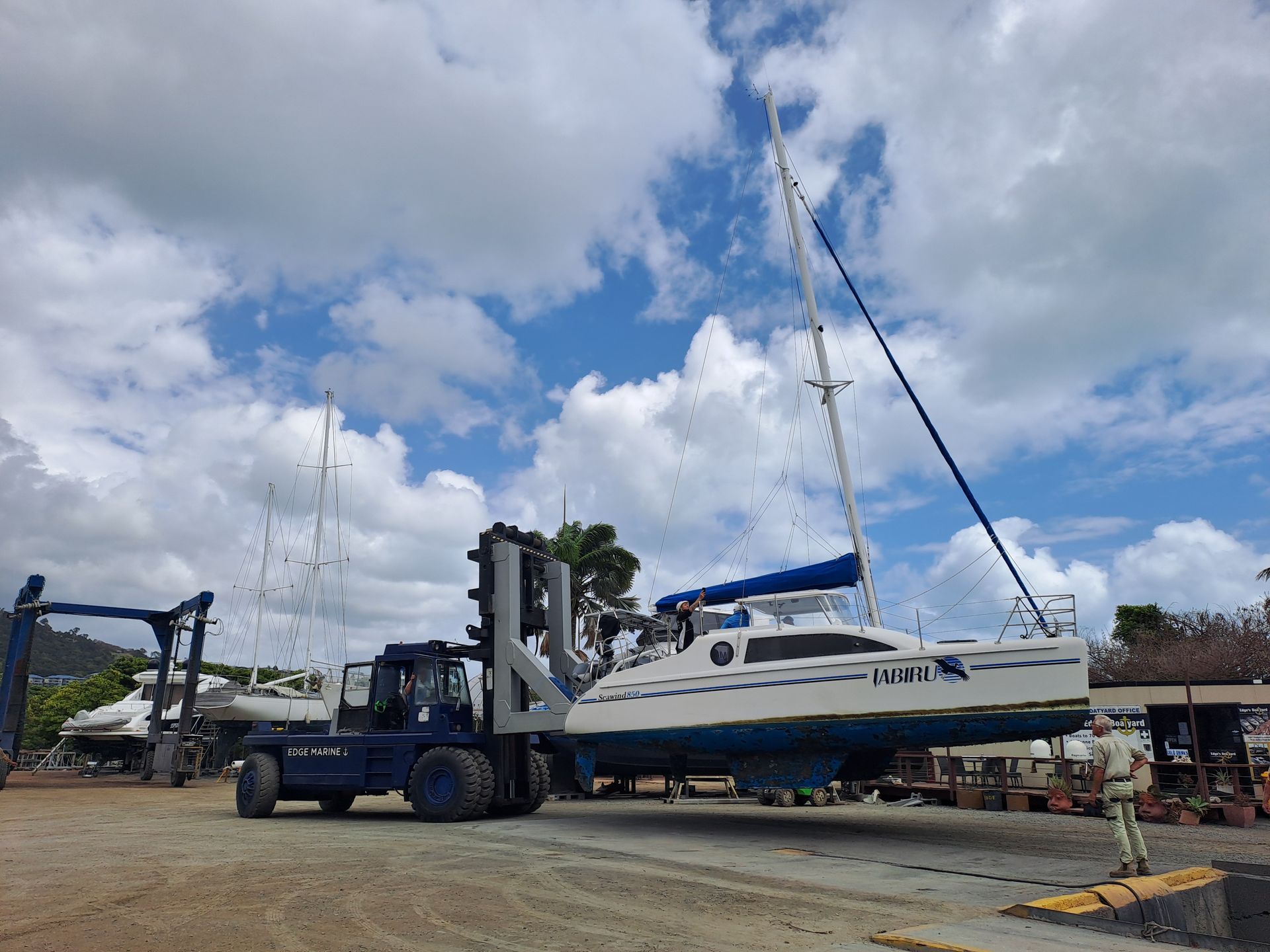 A boat is being lifted by a forklift in a marina — Edge's Boatyard In Jubilee Pocket, QLD