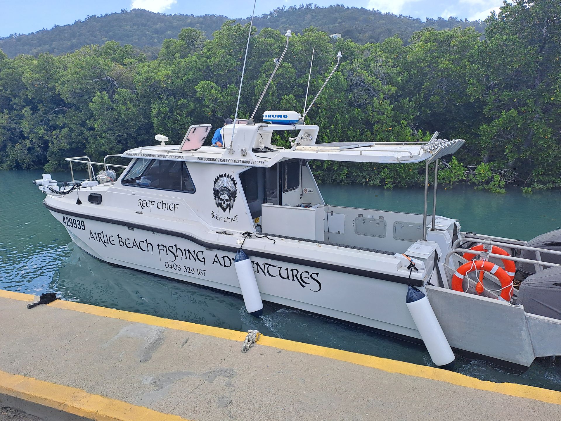 A white boat with a skull on the side is docked at a dock — Edge's Boatyard In Jubilee Pocket, QLD