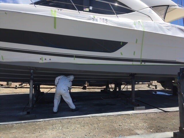 A Man In A White Suit Is Spray Painting Under The Boat — Edge's Boatyard In Whitsundays, QLD