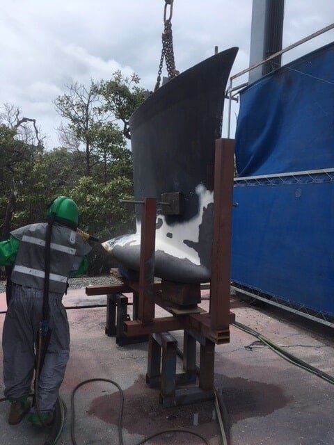 A Man Wearing A Green Hard Hat Is Working On A Part Of A Boat  — Edge's Boatyard In Jubilee Pocket, QLD