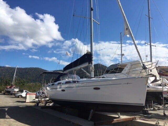 A White Sailboat Is Docked In A Marina With Mountains In The Background — Edge's Boatyard In Jubilee Pocket, QLD