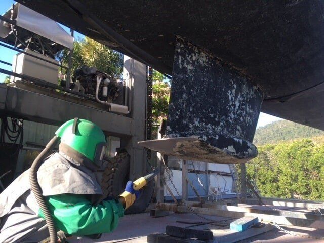 A Man Wearing A Green Helmet Is Sandblasting A Boat — Edge's Boatyard In Jubilee Pocket, QLD