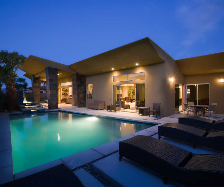 Modern house with a lit patio and turquoise pool at dusk