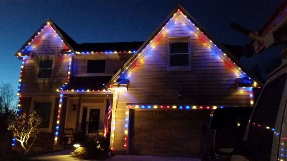 Suburban house at night decorated with colorful Christmas lights and a lit doorway