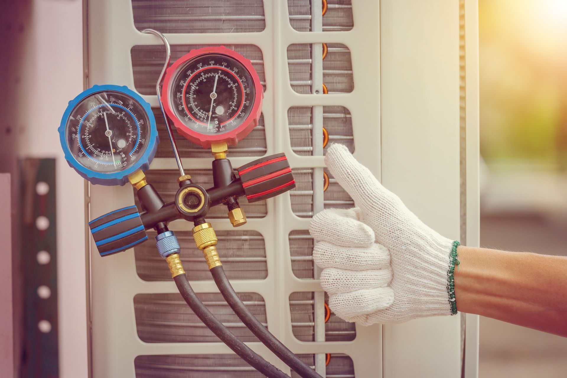 Gloved hand checking HVAC gauges attached to an outdoor air conditioning unit. Gloved hand checking HVAC gauges attached to an outdoor air conditioning unit.