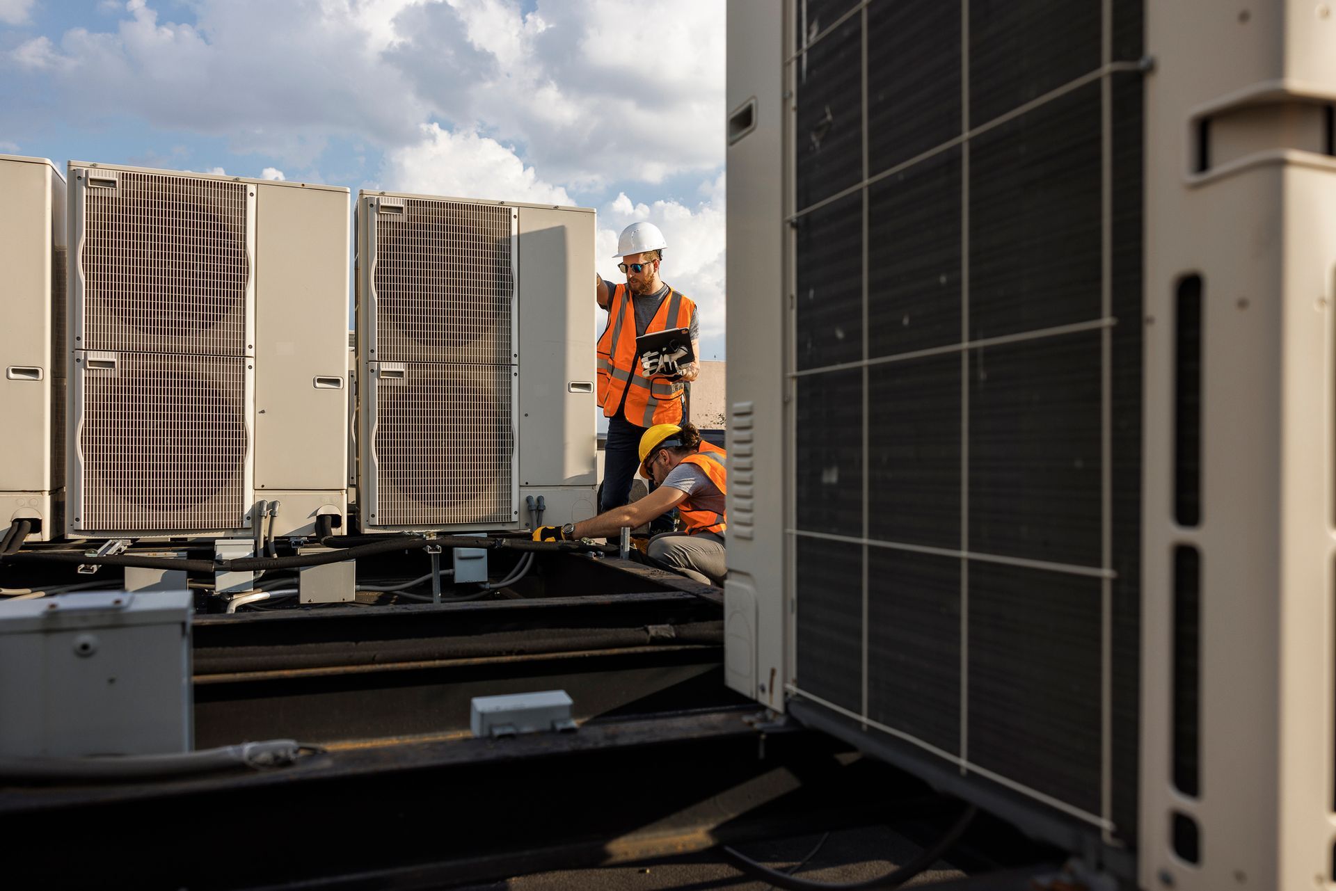 Two men on a roof check an HVAC system, highlighting their role as local HVAC contractors. Two men on a roof check an HVAC system, highlighting their role as local HVAC contractors.