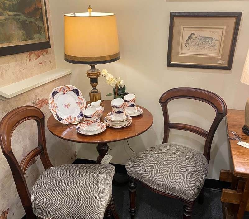 Cozy tea table with floral china, lamp, and two upholstered chairs in a corner nook