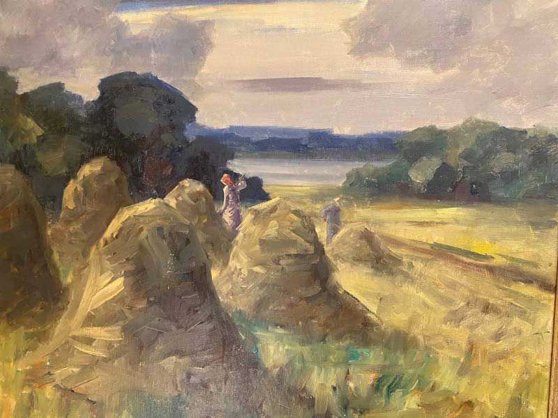 Hay bales in a golden field with a small figure in the distance under a cloudy sky