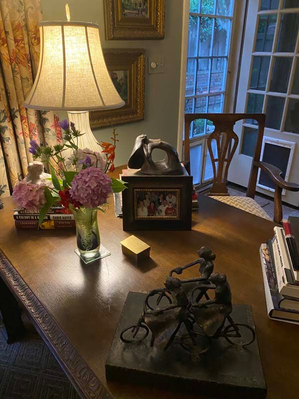Decorated wooden table with a lamp, flowers, framed photo, and metal bicycle sculpture in a cozy room