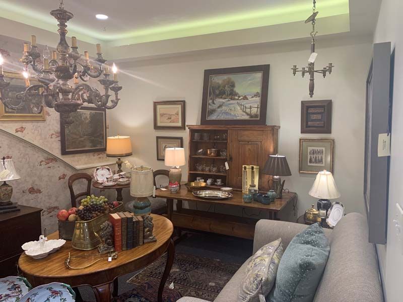 Cozy living room with chandelier, fireplace, antique furniture, framed art, and a sofa in the foreground