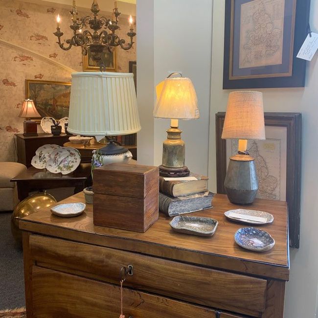 Wooden dresser with three lamps and decorative objects in a warmly lit home interior.