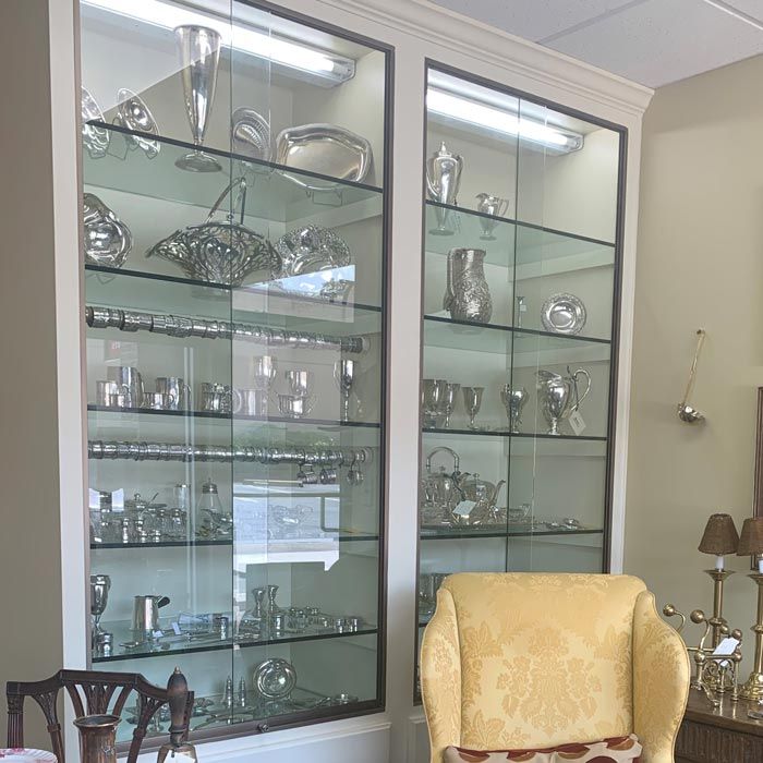 Glass display cabinets with silverware and glass decor beside a yellow armchair in a room