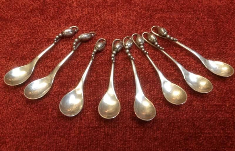 Eight silver spoon-shaped pendants fanned out on a red tablecloth