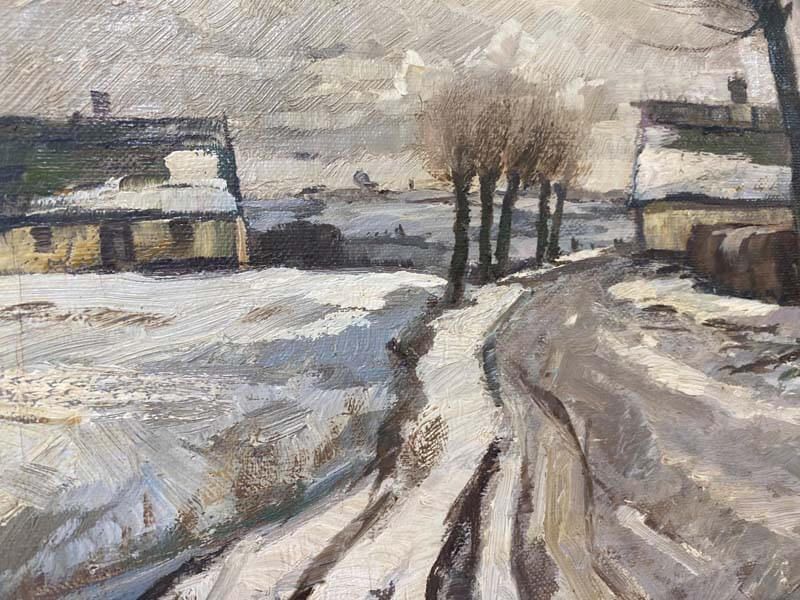 Snowy rural road curving past bare trees and farm buildings under a gray winter sky