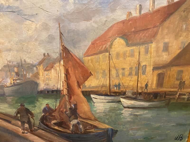 Sailing boats by a canal beside yellow riverside houses in a warm, hazy harbor scene