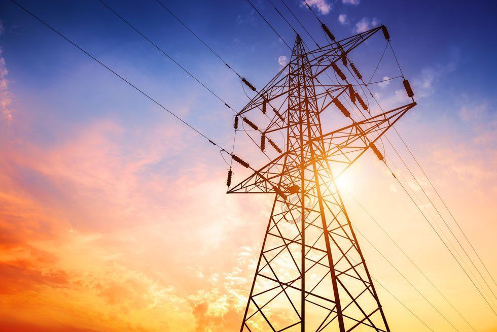 Power lines tower against a vibrant sunset sky.