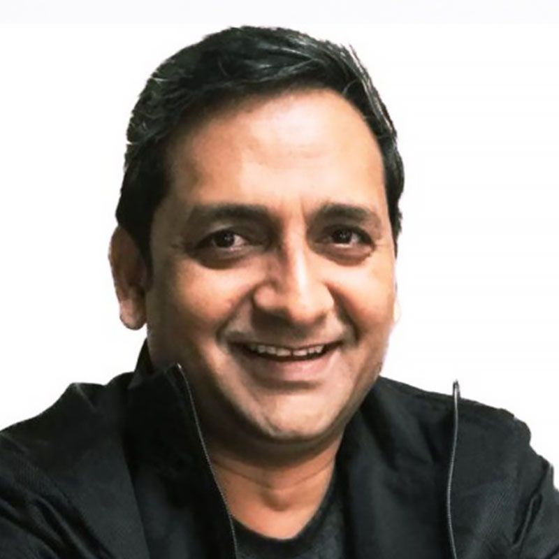 Man in black jacket smiling at the camera. White background.