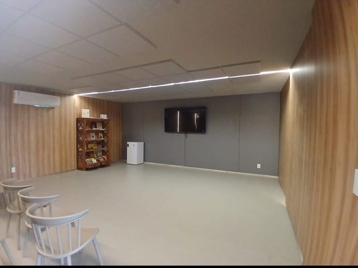 Sala de estar moderna e vazia com painéis de madeira, cadeiras, TV e prateleira para lanches.