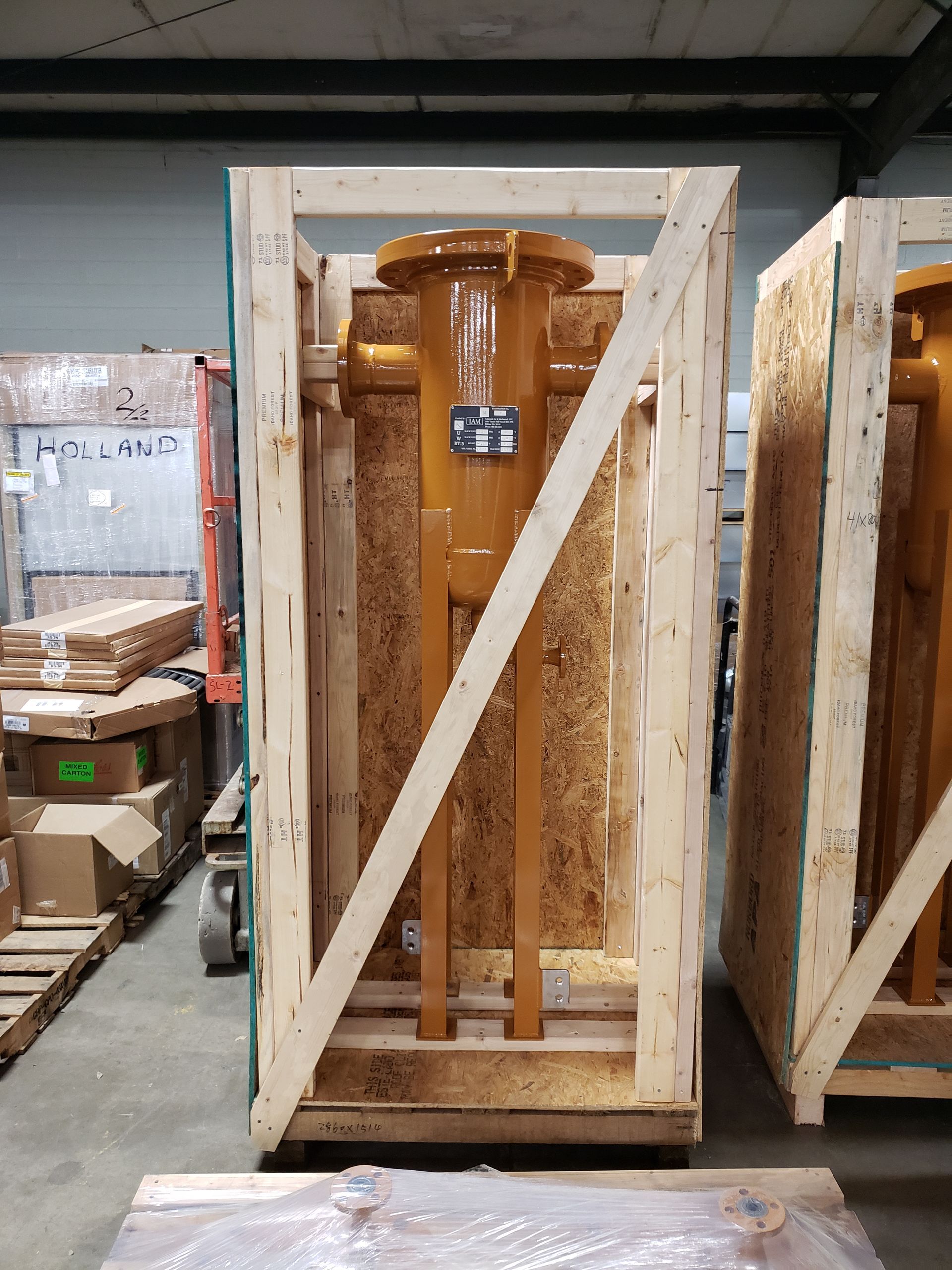 Large yellow industrial component inside a wooden crate, in a warehouse setting.
