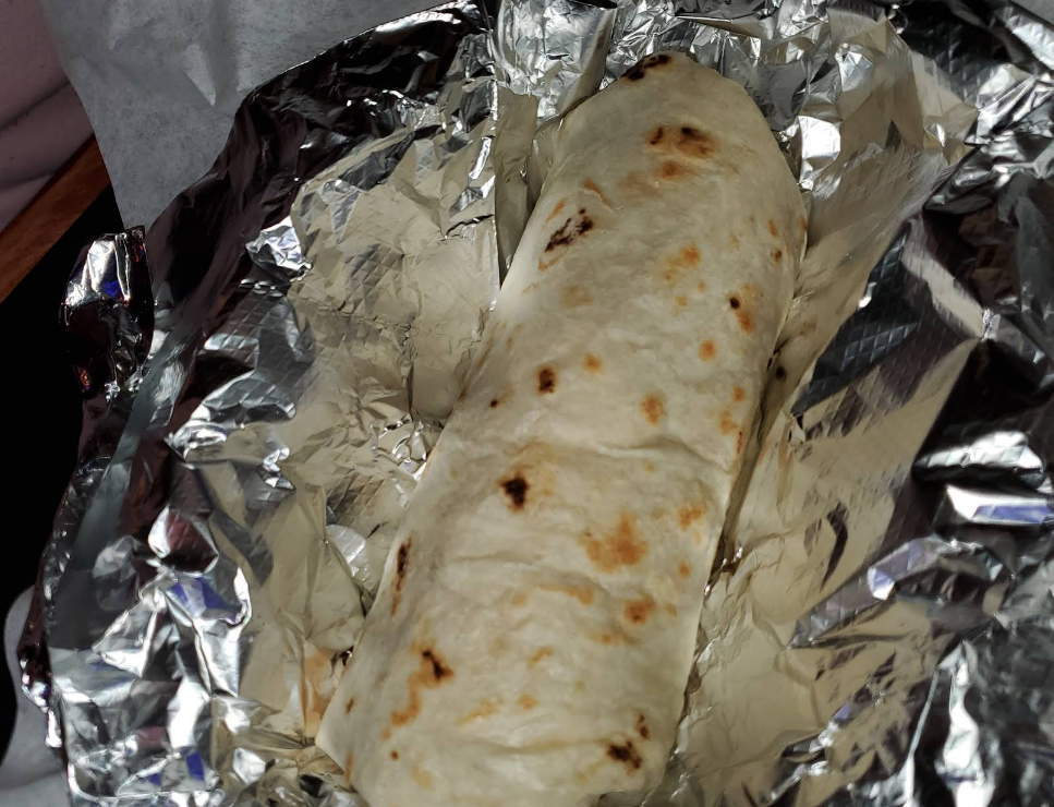 Burrito wrapped in foil, sitting in a gray and white wrapper.