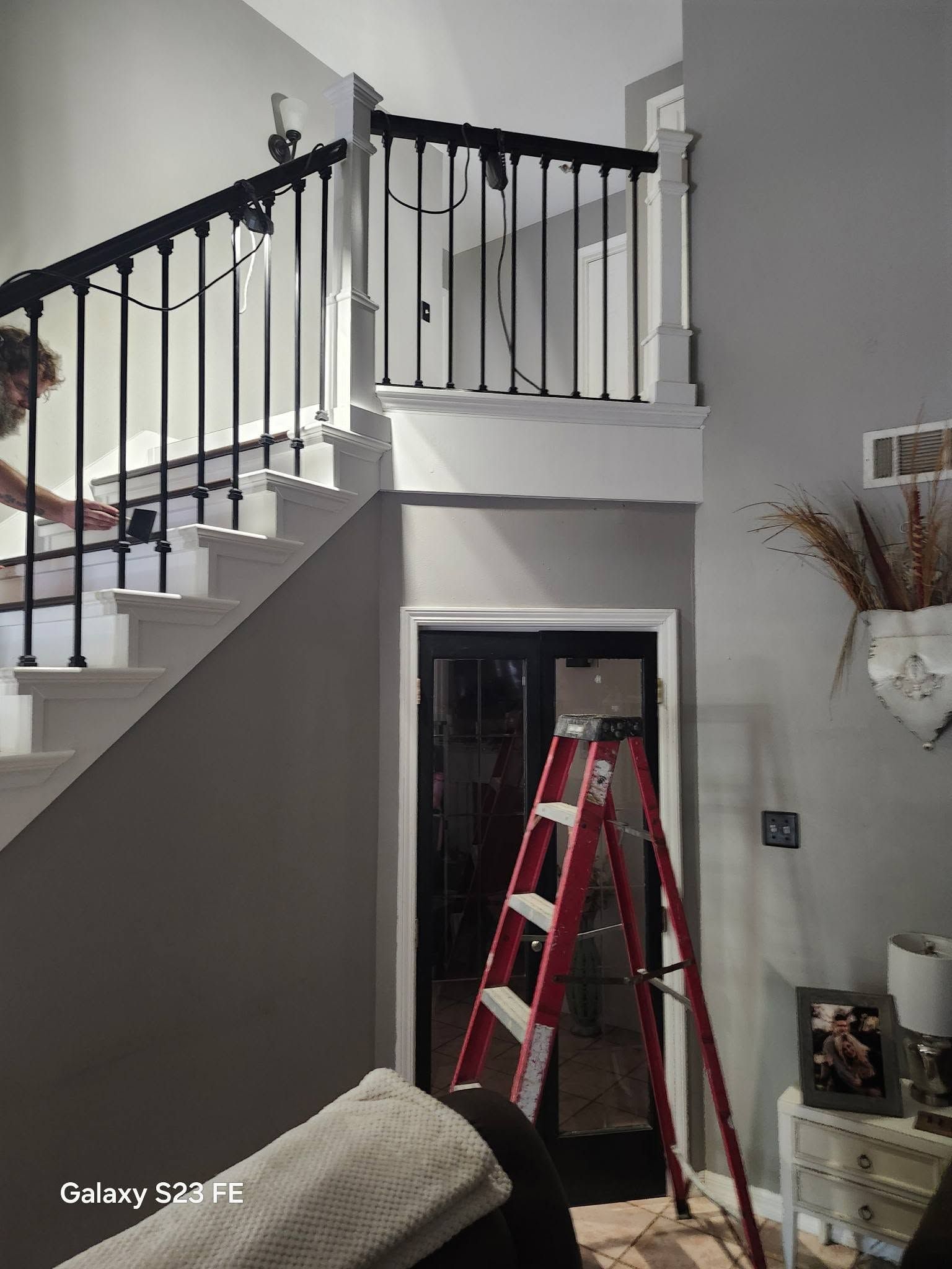 Staircase and hallway with a red ladder set up below a doorway in a home interior.