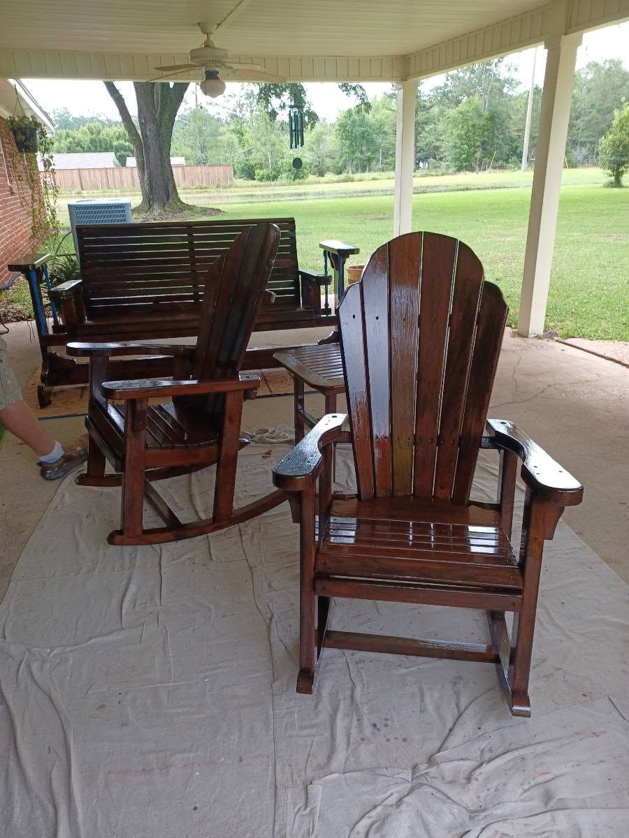 Wooden patio chairs on a covered porch overlooking a green yard