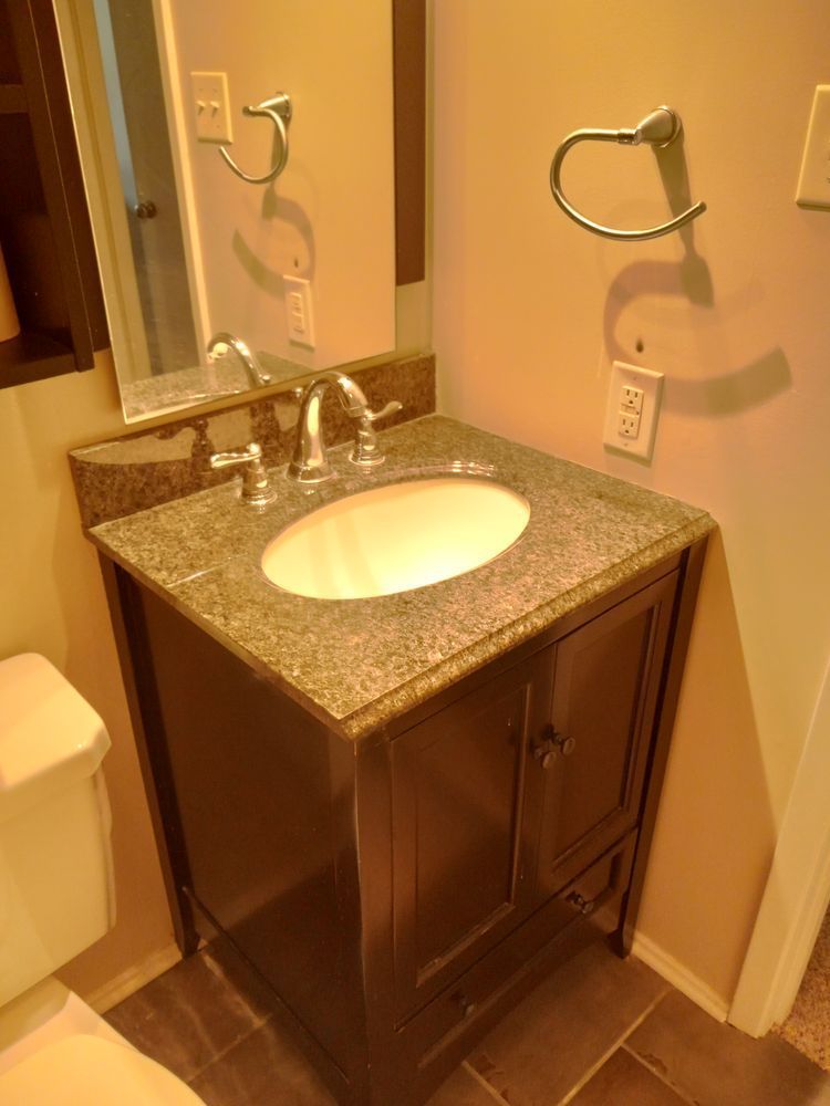 Small bathroom vanity with sink, mirror, towel ring, and granite countertop.
