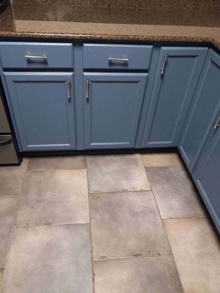 Blue kitchen cabinets above beige tile flooring in a corner kitchen