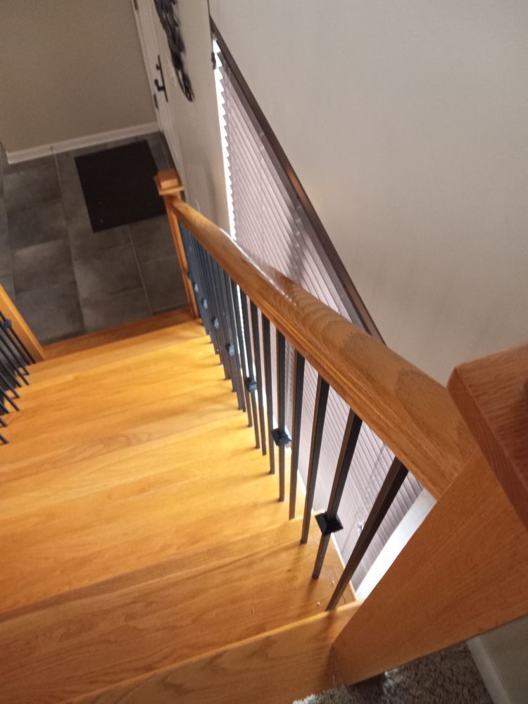 Staircase with wooden steps and railing, viewed from the top looking down into a hallway below