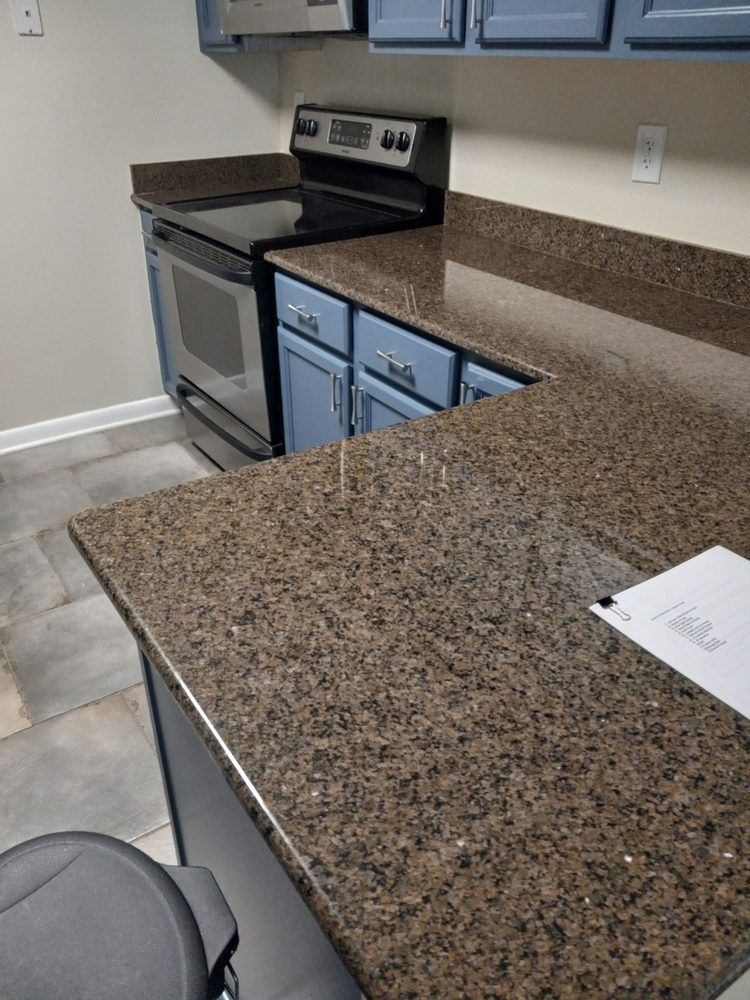 Brown speckled kitchen countertop with stainless stove and blue cabinets in a tiled room