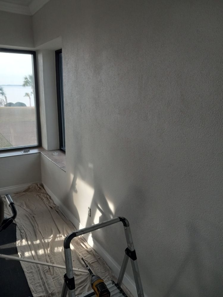 Sunlit empty room with a ladder, unfinished walls, and a window overlooking a fence.