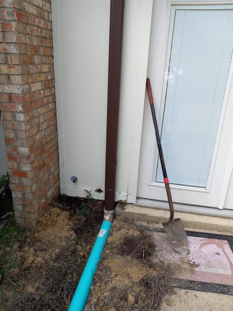 Outdoor side yard with a blue pipe, shovel, and door by a brick wall and downspout.