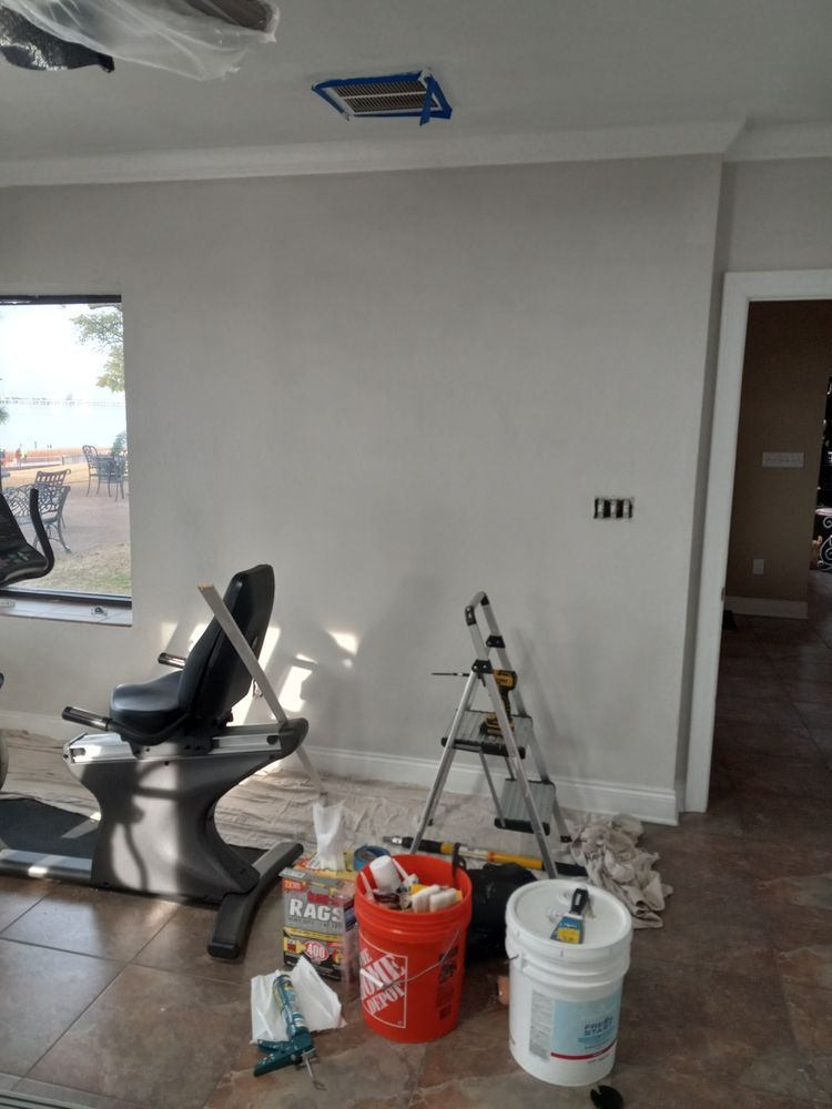 Partially renovated room with a treadmill, ladder, paint buckets, and supplies on the floor