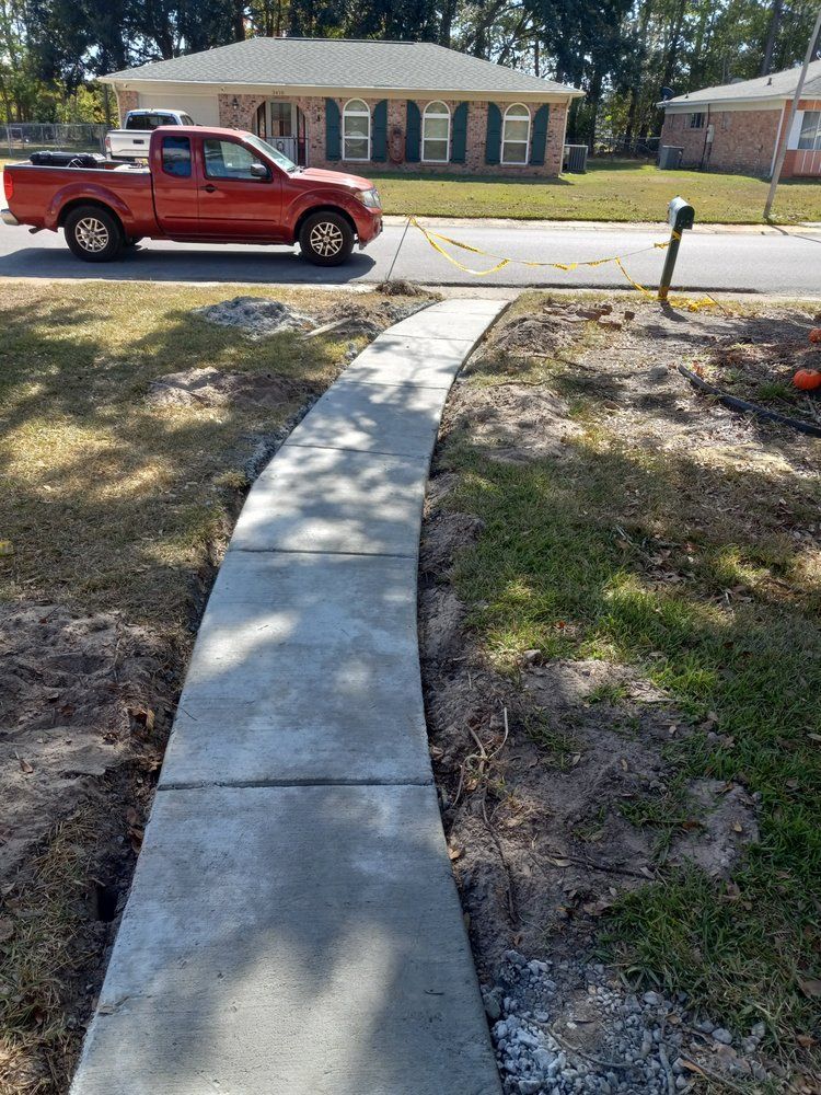New concrete sidewalk leading across a yard to a red pickup truck on a residential street