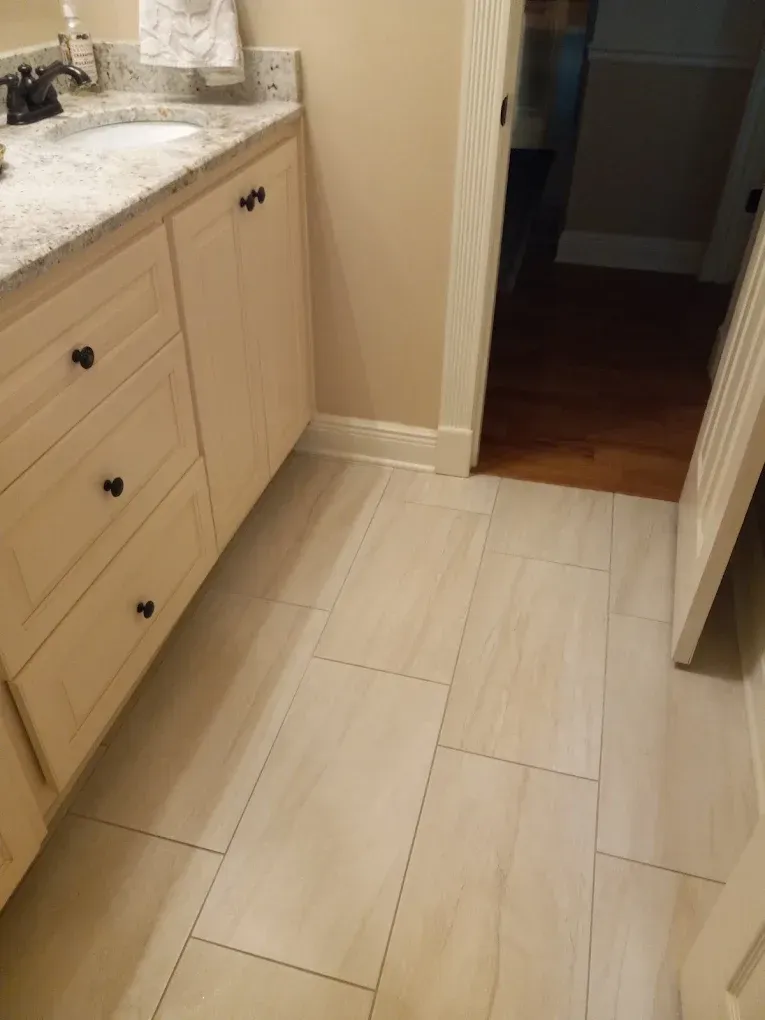 Bathroom hallway with light wood floor, beige cabinets, and granite countertop