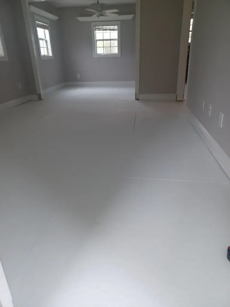 Empty white room with windows, gray walls, and a ceiling fan.