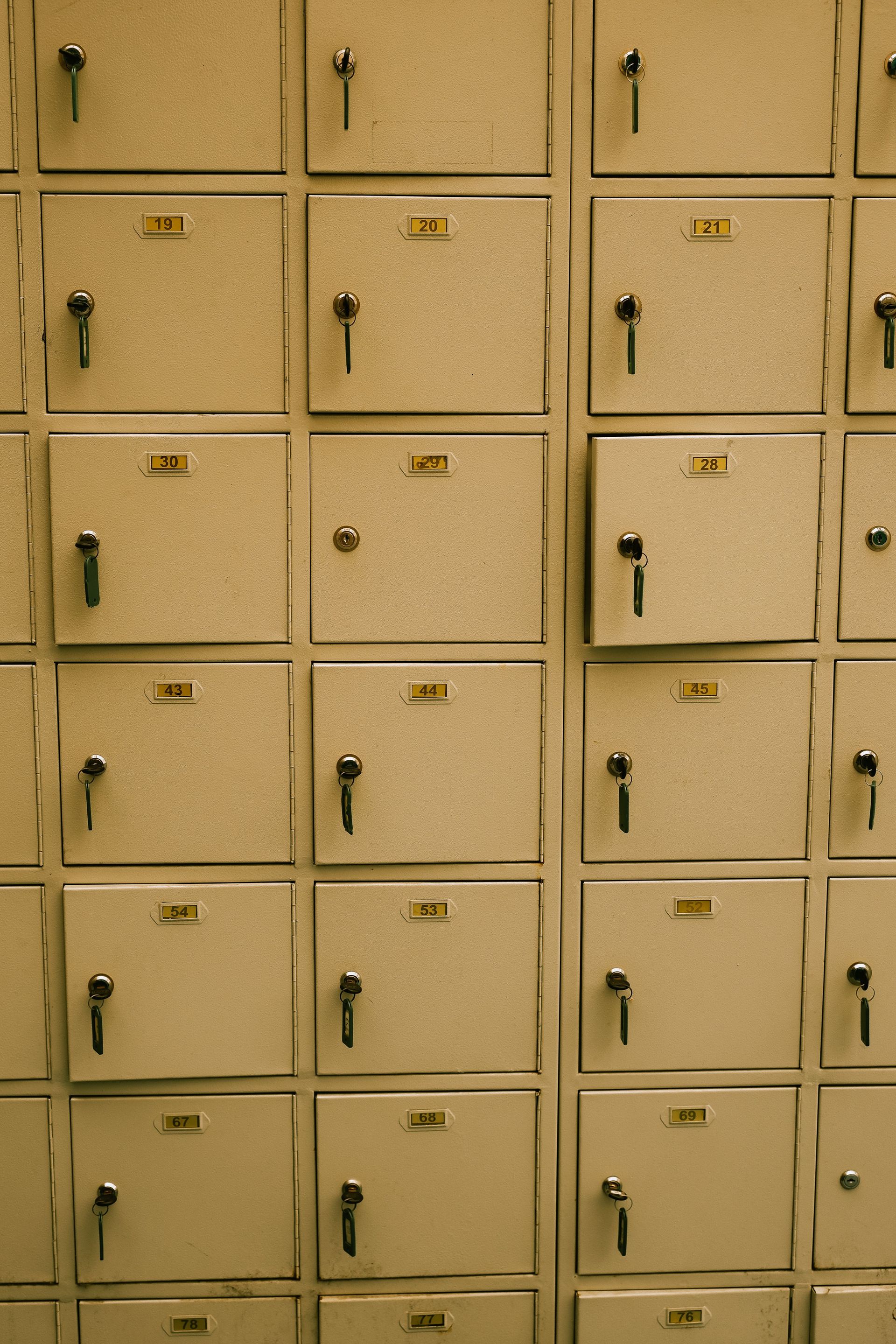 Row of beige school lockers with black handles and number labels.