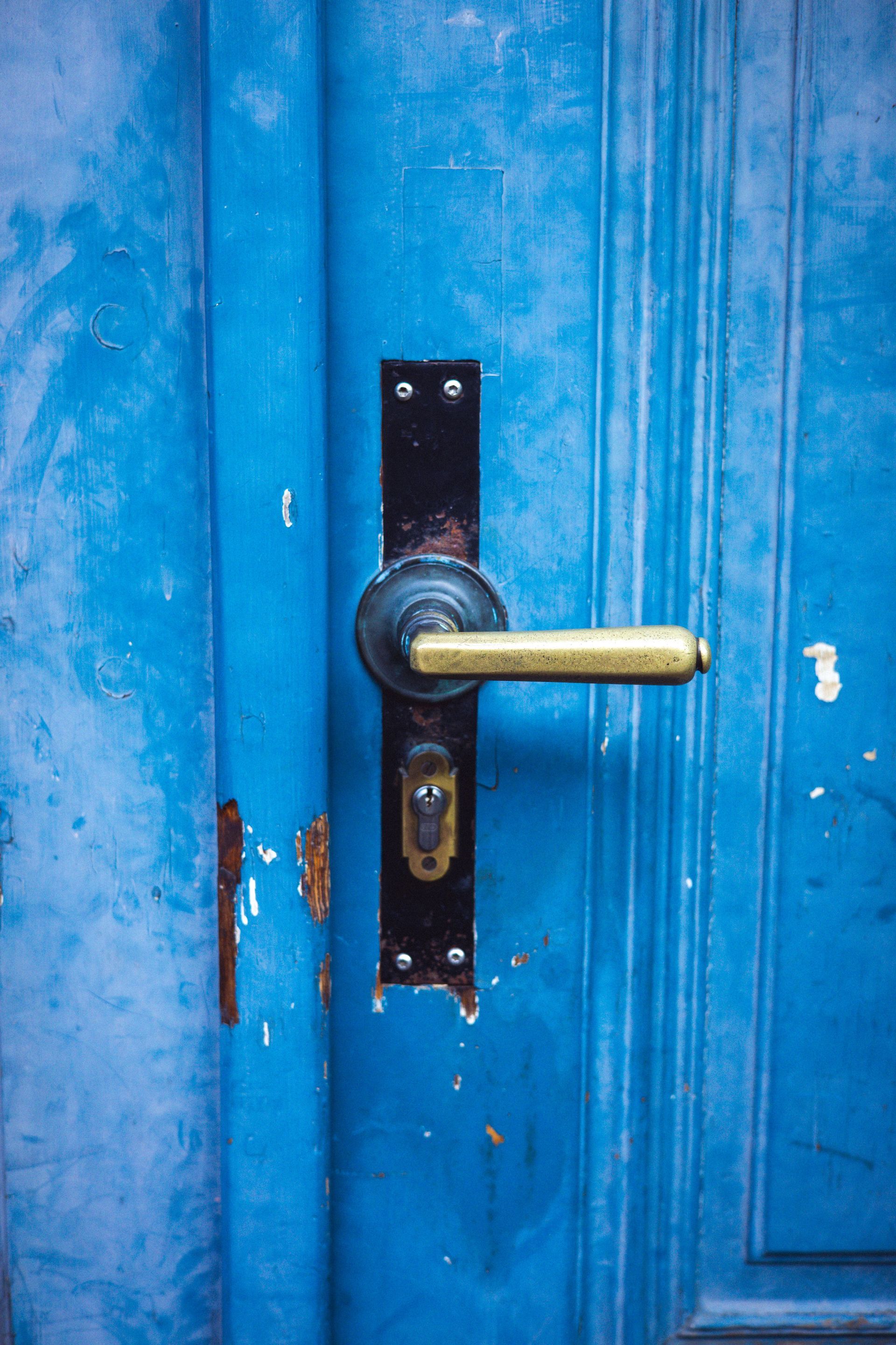 Blue wooden door with brass handle and keyhole plate close-up