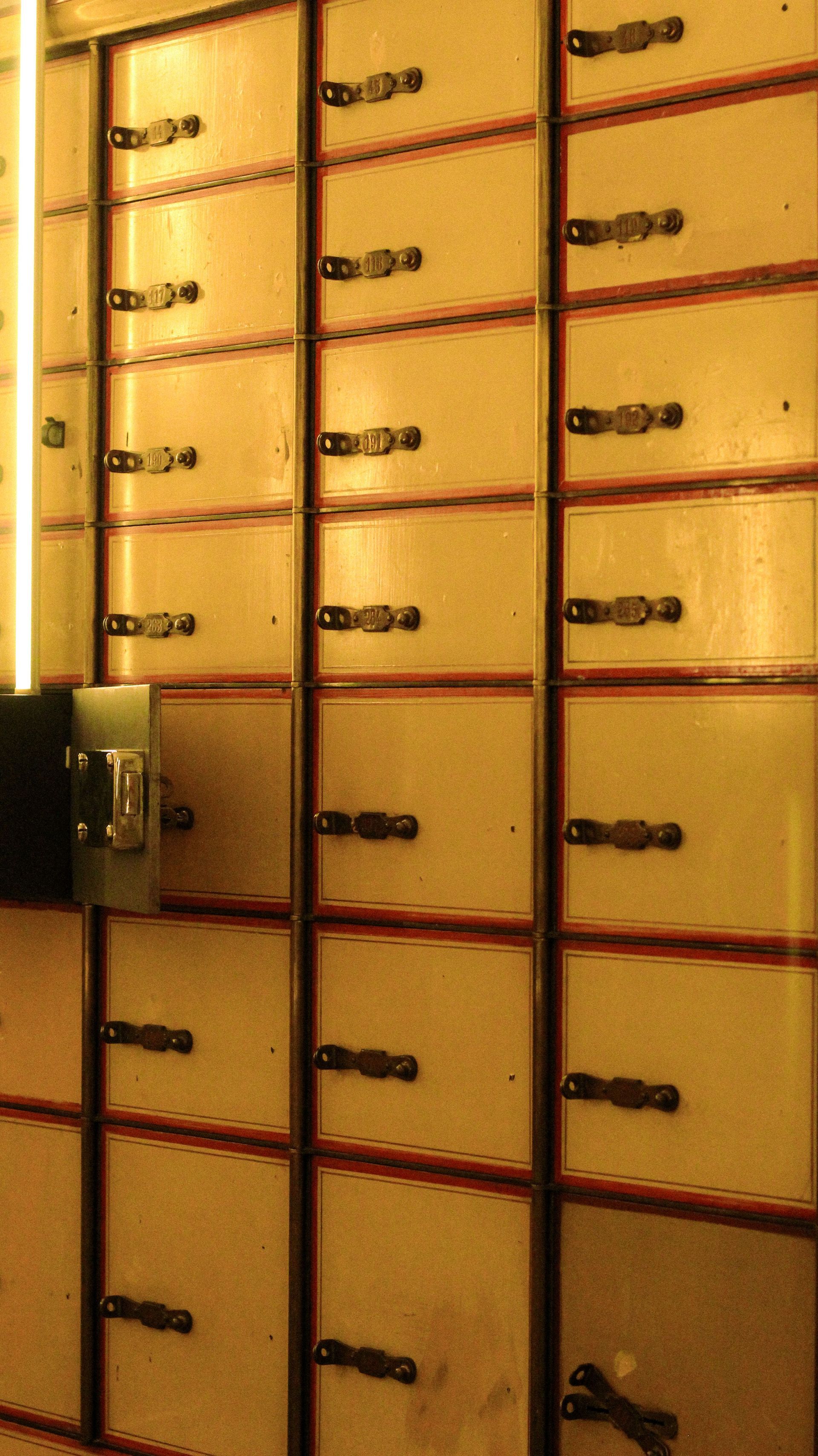 Rows of yellow lockers with dark handles in a hallway or storage area