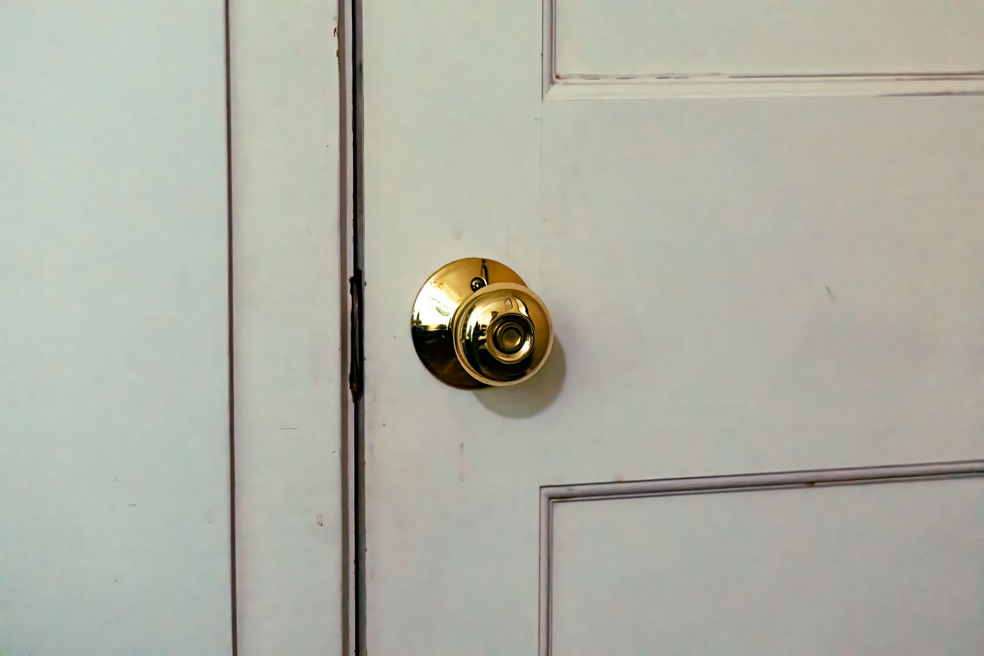 Close-up of a white door with a brass doorknob and lock.