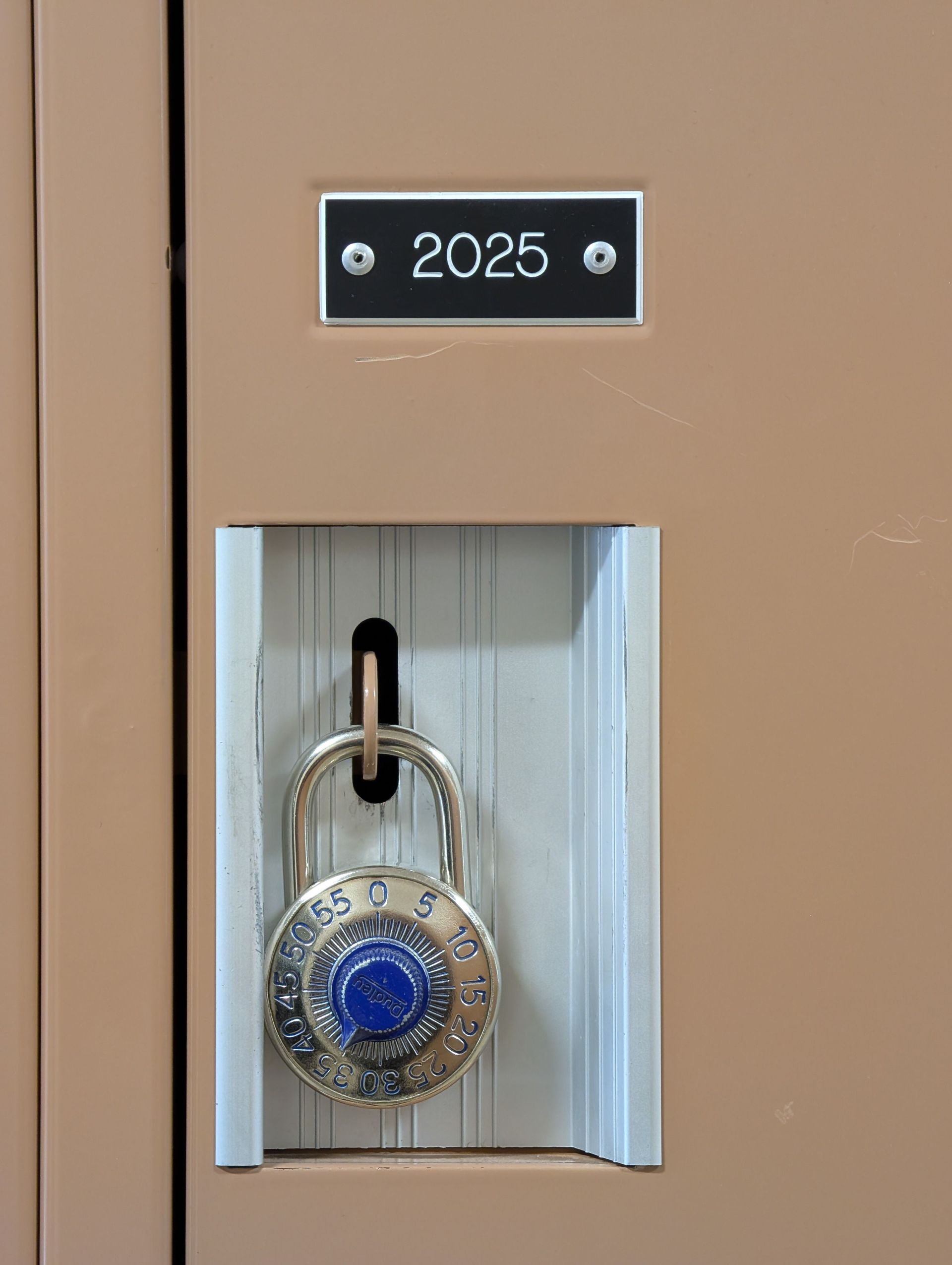 Padlock with blue combination dial in a locker labeled “2025”