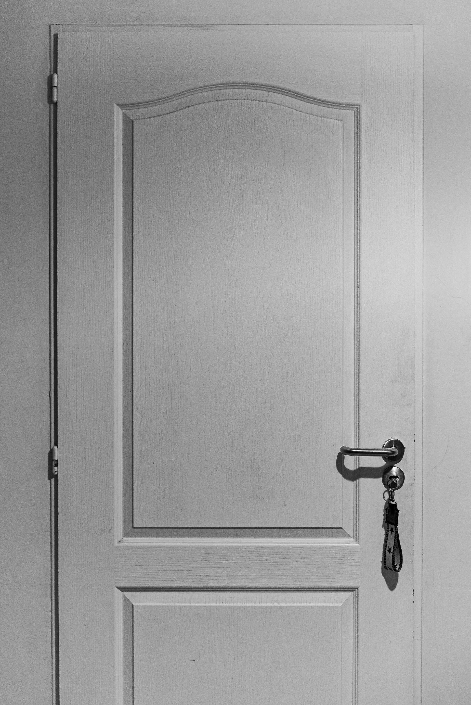 A white interior door with decorative panels and a dark handle holding keys.