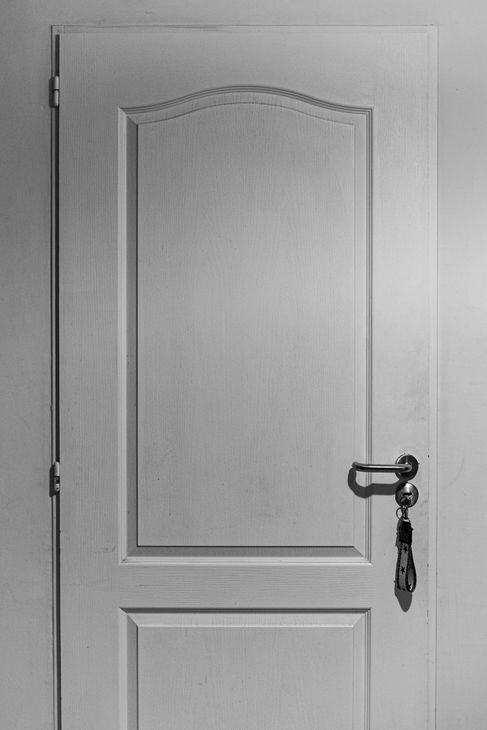 White interior door with a brass handle and key hanging from it.